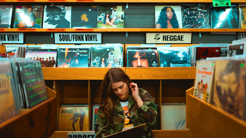 Girl in record store contemplating how to distribute her own music